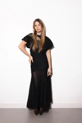 Vestido largo negro de encaje transparente con diseño geométrico, mangas cortas con volados y cuello alto.