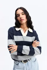 Buzo de tejido liviano con diseño de rayas horizontales en azul marino y gris, cuello tipo polo en color crema y mangas largas.