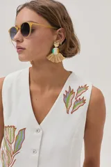 Chaleco blanco de gabardina con bordados florales y cierre frontal con botones forrados en la misma tela.