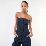 Top tipo bustier confeccionado en denim azul oscuro, con cierre frontal mediante botones metálicos y costuras a la vista en contraste.