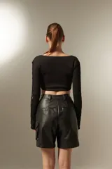 Top cropped negro de algodón, con escote redondo y mangas largas con aberturas para los pulgares.