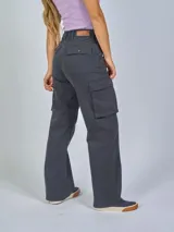 Pantalón cargo gris oscuro de tiro alto y pierna ancha, confeccionado en gabardina de algodón elastizada. Cuenta con bolsillos laterales, bolsillos plastrón con fuelle y solapa a media pierna, y bolsillos traseros con solapa y botón.