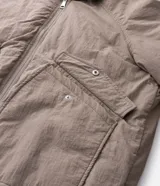 Campera bomber masculina de poliamida, con cuello, puños y ruedo de tejido elástico. Presenta cierre frontal con cremallera, dos bolsillos laterales con solapa y botón, y un pequeño bolsillo con cierre en una de las mangas.