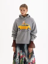 Buzo con capucha de calce amplio, color gris melange, con estampa frontal de un conejo sobre un auto amarillo. Posee mangas largas con puños acanalados.