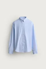 Camisa celeste de corte relaxed fit confeccionada en algodón, con cuello con botones y manga larga.