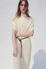 Vestido midi de punto color azul marino, de corte holgado, con cuello subido y manga corta vuelta. Incluye un cinturón fino efecto piel con hebilla metálica dorada.