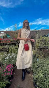 Bandolera compacta color rojo con textura de cuero, correa regulable y desmontable con diseño de rayas rojas y blancas. Cuenta con bolsillos frontales y cierre, interior forrado en tela.