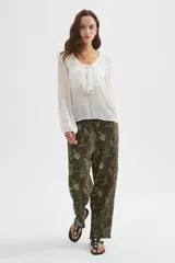 Pantalón tipo babucha de viscosa, color verde militar con estampado floral en tonos claros. Presenta un diseño holgado y cintura elástica con cordón ajustable.