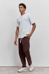 Remera de algodón color marrón chocolate, de corte clásico y cuello redondo, con un pequeño estampado gráfico en el pecho.