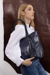 Cartera tote de cuero genuino color azul marino, con doble asa de hombro, costuras verticales y detalle de borla de flecos colgante.