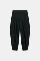 Pantalón bombacho de tiro medio confeccionado en lino, color negro, con pernera abullonada y bajo acabado en puño con botón.