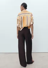Camisa de lyocell con estampado de rayas verticales en tonos naranja, marrón y beige. Tiene cuello camisero, manga larga con puños abotonados y cierre frontal con botones.
