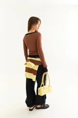 Top de manga larga con diseño de doble capa superpuesta, combinando una capa superior negra y una inferior marrón. Presenta cuello redondo, ajuste al cuerpo y detalle de bordado BG en la parte inferior.