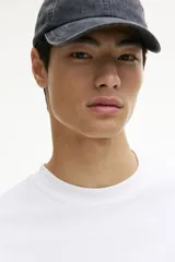 Remera blanca de manga larga en punto de algodón de peso medio, con cuello redondo acanalado, hombros caídos, puños acanalados y bajo recto. Presenta un corte holgado.