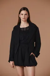 Saco corto de corte sastrero en color negro, con solapas clásicas, cierre frontal de botones y mangas largas con detalle de trabillas en los puños.