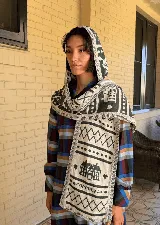 Balaclava tejida con diseño de capucha integrada y bufanda larga, confeccionada en una mezcla de algodón y acrílico con motivos geométricos en tonos rojo y azul.