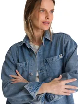 Camisa oversize de denim azul de la marca Cat, de manga larga con puños abotonados, cuello camisero y cierre frontal de botones. Presenta doble bolsillo en el pecho con etiqueta de la marca y dobladillo tipo cola de camisa.