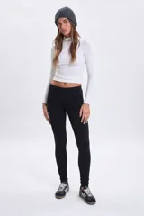 Legging de corte ajustado en color negro, confeccionado en tejido elástico de tiro medio.
