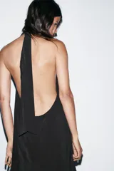 Vestido midi de tejido fluido color negro, con cuello halter anudado en la nuca y escote en pico.