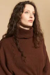 Poncho de tejido de punto color gris, con cuello alto y mangas amplias de diseño holgado.
