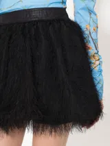 Minifalda negra con flecos de hilo y cintura de tela lisa.