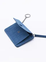 Billetera plateada con textura símil piel de cocodrilo, cierre de cremallera superior y solapa frontal con botón a presión.