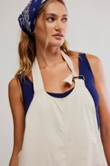 Enterito de inspiración laboral confeccionado en tejido de algodón ligero, color blanco, con top tipo halter, botones laterales y piernas holgadas.