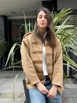 Chaqueta de abrigo color tostado, estilo militar, con detalles de apliques en cuerina marrón en los hombros, el cuello y las presillas frontales con botones metálicos dorados.