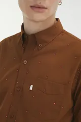 Camisa de manga larga color marrón con estampado de pequeños puntos, cuello abotonado y bolsillo frontal en el pecho.