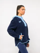 Buzo de micropolar color bordó con capucha, cierre frontal parcial y detalles en color crema. Presenta el logo de Umbro y el escudo del Club Nacional de Football bordados en el frente.
