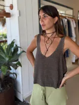 Blusa de tejido de punto con acabado brillante, escote en V profundo y espalda abierta. Presenta un diseño holgado y sin mangas.