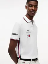 Chomba de corte regular confeccionada en algodón elástico, con cuello polo y cartera de dos botones. Presenta ribetes distintivos en cuello y puños, cinta lateral y múltiples logos bordados que incluyen Tommy Hilfiger, Cadillac Formula 1 Team y Pirelli.