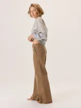 Pantalón de jean color marrón, de corte recto y tiro medio. Presenta bolsillos laterales con detalle de costura a contratono y cierre frontal con botón.