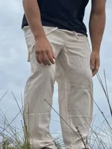 Pantalón de lino beige y crudo a rayas, de corte ancho y relajado.