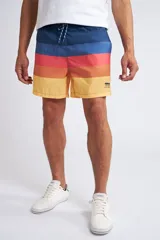 Short de baño con cintura elástica y cordón ajustable, confeccionado en tela ligera de secado rápido. Presenta un estampado botánico integral en tonos amarillos, blancos y azules, con dos bolsillos delanteros y uno posterior.