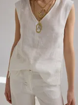 Top sin mangas de lino color blanco, con escote en V y costuras decorativas a la vista en tono contrastante. Presenta un corte recto y holgado.