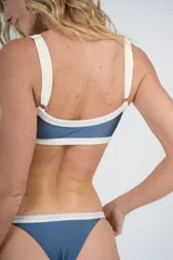 Conjunto de bikini azul con ribetes blancos, compuesto por un corpiño tipo top con breteles finos y una bombacha colaless regulable.