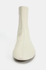 Botín plano de piel en color blanco roto, con diseño minimalista de caña baja, punta redonda y costuras decorativas. Cuenta con cierre mediante cremallera lateral y suela plana.