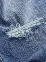 Jeans de algodón elástico, lavado a la piedra azul oscuro, con talle medio y pierna estrecha en el tobillo. Presenta roturas en ambas piernas.