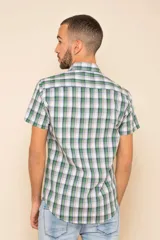 Camisa de manga corta con estampado de cuadros en tonos verdes, azules y blancos. Presenta cuello clásico, cierre frontal con botones y dos bolsillos delanteros con solapa.