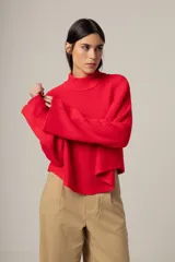 Sweater de tejido de punto en color rojo, con cuello alto y mangas largas acampanadas. Presenta un diseño de corte recto y holgado.