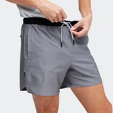 Short deportivo de hombre color gris, con cintura elástica negra y cordón de ajuste blanco. Presenta un corte por encima de la rodilla y bolsillos laterales.