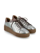 Sneaker de cuero color plateado con textura efecto cocodrilo, suela plataforma de goma marrón y cordones de algodón.