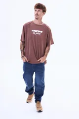 Remera de algodón con efecto lavado, color marrón, de corte oversize, cuello redondo y manga corta. Presenta una estampa frontal con el texto 'CONFIRM the future' en color blanco.