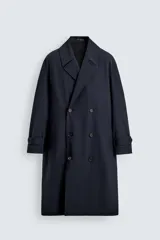 Trench de corte relajado confeccionado en tejido con viscosa, de color azul marino. Presenta cuello con solapas de muesca, cierre frontal de botonadura cruzada, mangas largas con puños ajustables mediante trabillas y bolsillos de vivo en la cadera. Incluye una abertura central en la espalda.