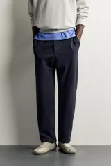 Pantalón negro confeccionado en mezcla de algodón, con cintura elástica, bolsillos frontales y cierre con cremallera y botón.