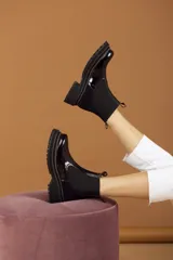 Botas tipo Chelsea con paneles elásticos laterales, confeccionadas en una combinación de cuero liso y gamuza en tonos marrones. Presentan una suela track robusta y dentada en color beige.