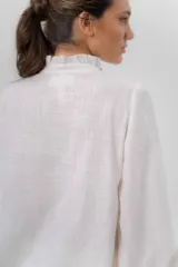 Camisa de manga larga color beige con diseño a rayas sutiles, cuello mao con volados y abertura frontal con detalles de volados a un lado.