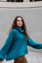 Buzo de tejido de punto en mezcla de lana y alpaca, color gris. Presenta una silueta amplia con cuello tipo polo que incluye broches para convertirlo en polera, mangas largas con puños y un diseño de tejido horizontal.