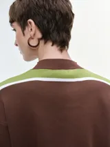 Buzo de punto con diseño de franjas horizontales en azul y blanco sobre fondo negro. Presenta cuello redondo, mangas caídas con puños elastizados y un corte holgado.